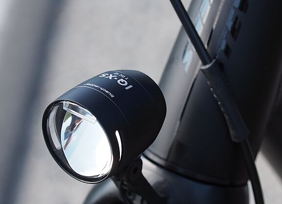 Schwarzer LED-Fahrradscheinwerfer am silbernen Fahrradlenker montiert.